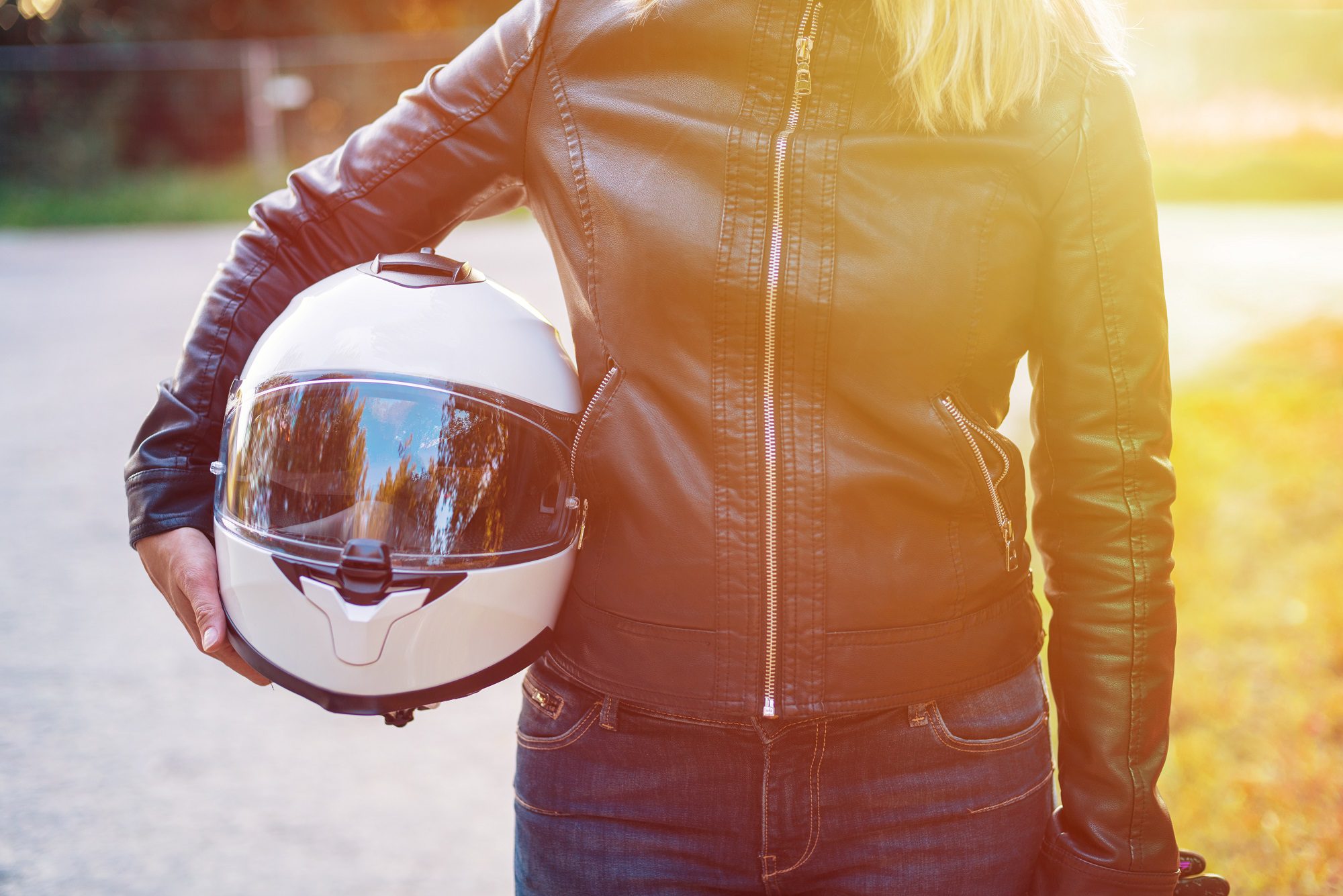 Woman in leather jacket holds motorcycle helmet